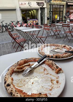 Zwei leere Pizzateller mit Krustenresten stehen auf einem Tisch in einem Restaurant im Freien Stockfoto