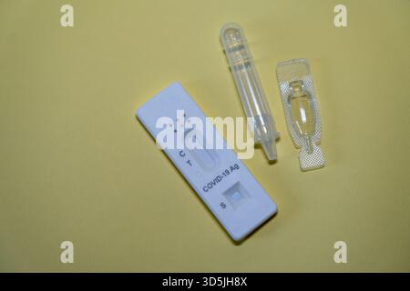 Eine flache Ablage von Komponenten des COVID-19 AG-Rapid-Antigen-Testkits auf einer weichen gelben Oberfläche für den häuslichen oder klinischen Einsatz. Stockfoto