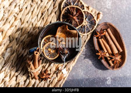 Blick von oben auf eine Tasse Glühtee mit verschiedenen Gewürzen auf einer rustikalen Tischmatte Stockfoto