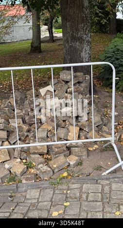 Stapel Betonziegel hinter einem Metallzaun, Baustellenhintergrund im Freien. Mobiles Foto Stockfoto