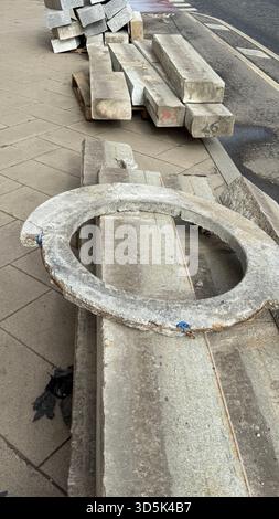 Betonbaumaterialien, gestapelt auf Gehwegen, einschließlich kreisförmiger und rechteckiger Platten. Mobiles Foto Stockfoto