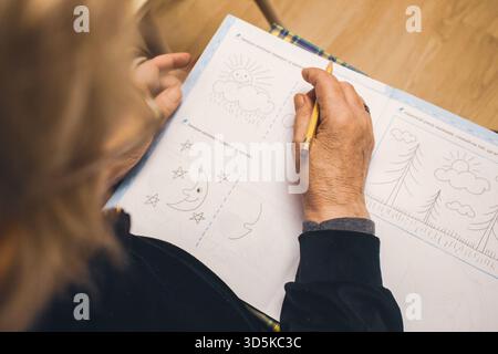Seniorenlebenskonzept. Alte Hände mit Falten halten Stift und Zeichenaufgabe. Alte Frau zeichnet Bilder für die Restauration. Kunsttherapiekonzept. Stockfoto