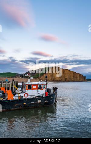 Baggerschiff im West Bay Harbour bei Sonnenuntergang, das Schlamm aus dem Hafen mit Druckwasser beseitigt. Stockfoto