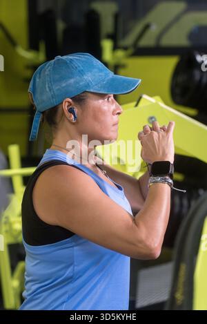 Eine Frau mittleren Alters, die Squats macht, eine Mütze und blaue Sportbekleidung trägt. Stockfoto