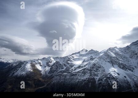 Bergkette, steile schneebedeckte Felshänge und Gipfel und große bizarre Wolken. Selektiver Fokus Stockfoto