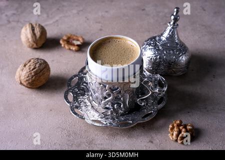 Kleine schöne traditionelle Tasse mit türkischem Kaffee auf beigefarbenem Hintergrund. Walnüsse liegen neben einer Kaffeetasse. Selektiver Fokus Stockfoto