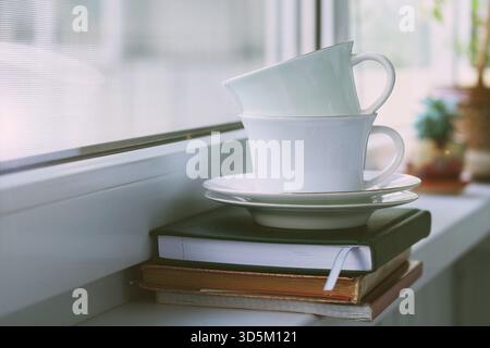 Komposition zweier Porzellan-Teetassen mit Untertassen auf der Fensterbank. Selektiver Fokus Stockfoto