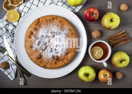 Nahaufnahme von oben auf einen Apfelkuchen umgeben von frischen Reifen Äpfeln. Hausgemachte Kuchen mit Obst der Saison, selbstgemacht. Selektiver Fokus Stockfoto