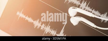 Podcast-Aufzeichnung. Ohrstöpsel und Soundtrack am Tablet. Graues Schwarzweiß. Hörbuch und Podcasting. Audiotechnologie. Hausschulunterricht. Episode bearbeiten Stockfoto