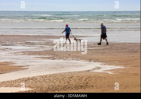 Zwei Leute und Hund am abgelegenen Strand Stockfoto