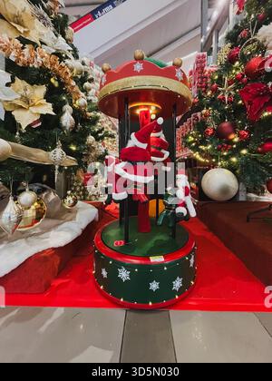Balikpapan, Indonesien - 16. November 2025. Eine festliche, motorisierte Ausstellung mit Miniatur-Weihnachtsmannsfiguren auf einem Karussell ist von Dekor umgeben Stockfoto