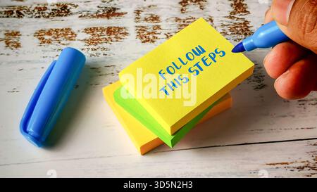 Befolgen Sie diese Schritte Anleitung Konzept mit Handschrift auf gestapelten bunten Haftnotizen Stockfoto