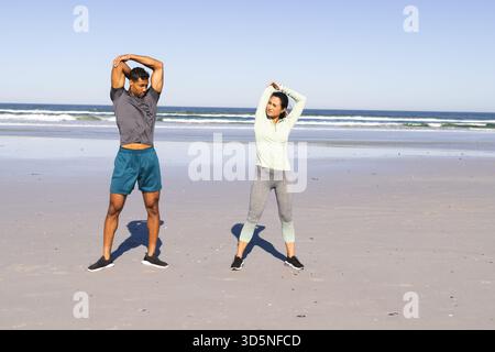 Sich am Strand ausstrecken, Paare, die morgens auf dem Meer trainieren, aktiv bleiben Stockfoto