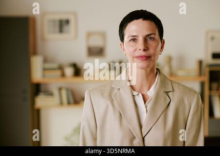 Porträt einer kaukasischen Frau mittleren Alters, die selbstbewusst im Büro lächelt Stockfoto