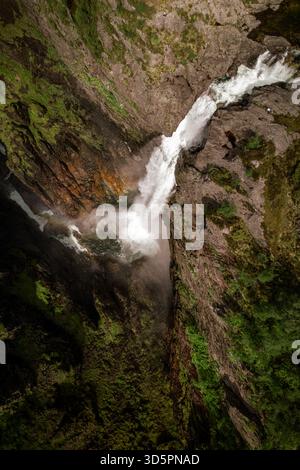 Blick aus der Vogelperspektive auf das kaskadierende Wasser, das sich über zerklüftete Klippen stürzt und einen Pfad durch moosbedeckte Felsen im Herzen des Canyons, Dirdal, Rogaland, N, führt Stockfoto