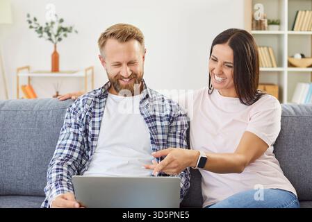 Glückliches Paar, das auf der Couch sitzt, im Internet surft oder Filme ansieht und die entspannende Zeit zusammen genießt. Stockfoto