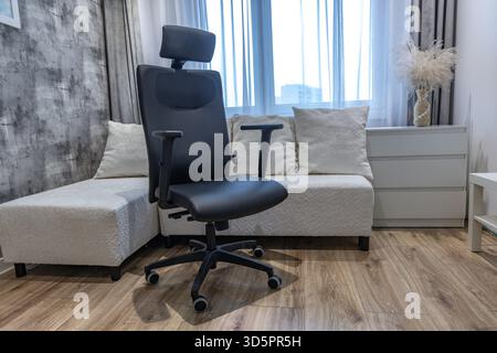 Ein schwarzer Drehstuhl aus Leder mit höhenverstellbarer Kopfstütze in einem modernen Büro eines Geschäftsmannes. Stockfoto