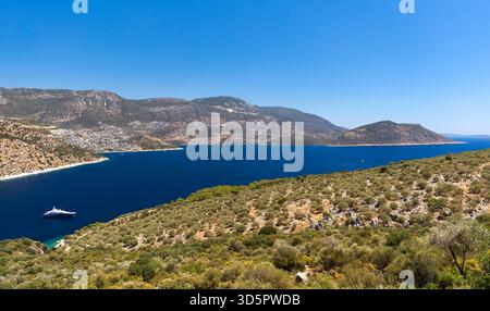 Ein Panoramablick auf die Küste mit tiefblauem Meer, zerklüfteten Hügeln und Olivenbäumen. Eine Luxusyacht liegt in der Nähe einer abgeschiedenen Bucht, die Luxus, Trav vermittelt Stockfoto