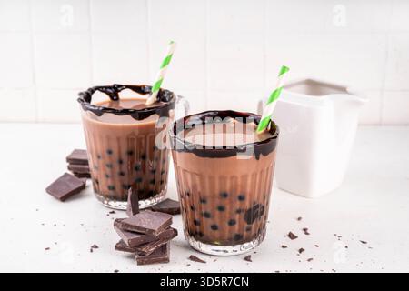 Leckerer heißer Schokoladen-Bubble-Tee. Kakao warm- oder kaltgetränk mit Tapiokakugeln und dunklem Schokoladensirup, süßes Dessertgetränk auf weißem Tisch mit c Stockfoto