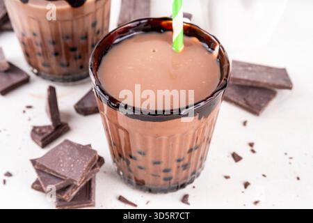Leckerer heißer Schokoladen-Bubble-Tee. Kakao warm- oder kaltgetränk mit Tapiokakugeln und dunklem Schokoladensirup, süßes Dessertgetränk auf weißem Tisch mit c Stockfoto