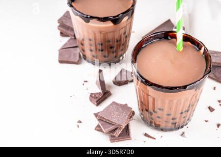 Leckerer heißer Schokoladen-Bubble-Tee. Kakao warm- oder kaltgetränk mit Tapiokakugeln und dunklem Schokoladensirup, süßes Dessertgetränk auf weißem Tisch mit c Stockfoto