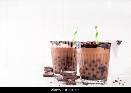 Leckerer heißer Schokoladen-Bubble-Tee. Kakao warm- oder kaltgetränk mit Tapiokakugeln und dunklem Schokoladensirup, süßes Dessertgetränk auf weißem Tisch mit c Stockfoto