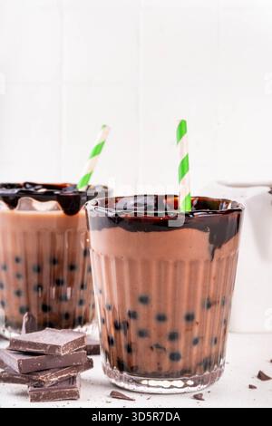 Leckerer heißer Schokoladen-Bubble-Tee. Kakao warm- oder kaltgetränk mit Tapiokakugeln und dunklem Schokoladensirup, süßes Dessertgetränk auf weißem Tisch mit c Stockfoto