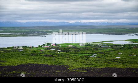 Der erhöhte Blick zeigt den Myvatn-See, umgeben von friedlichen Feuchtgebieten und lebhaftem grünen Gelände. Stockfoto
