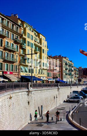 Farbenfrohe historische Gebäude und Straßencafés in der Altstadt von Nizza, Frankreich, unter einem klaren blauen Himmel. Traditionelle mediterrane Architektur Stockfoto
