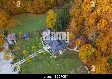 Blick von oben auf ein Gästehaus, umgeben von farbenfrohen Herbstwäldern im Valbona-Tal, Nord-Albanien. Stockfoto