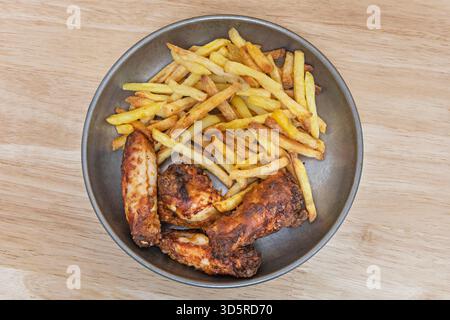 Gebratene Hähnchenflügel mit Julienne-Pommes und blauer Büffelsoße, begleitet von Sellerie- und Karottenstäbchen mit Ranch-Dip. Stockfoto