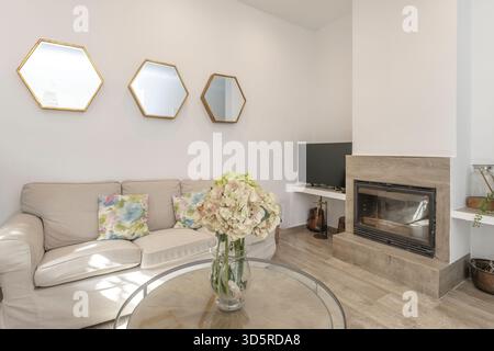 Vorderansicht eines modernen Wohnzimmers mit eingebautem Gaskamin und weißer Marmorverkleidung, integriert in die TV-Wand mit eingebauten Regalen. Stockfoto