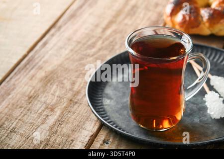 Türkischer schwarzer Tee. Eine Glasschale türkischer schwarzer Tee und knuspriger türkischer traditioneller Bagel auf altem Rustick-Hintergrund. Frühstücksgebäck-Konzept. Traditionelles türkisches Heißgetränk. Stockfoto