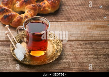 Türkischer schwarzer Tee. Eine Glasschale türkischer schwarzer Tee und knuspriger türkischer traditioneller Bagel auf altem Rustick-Hintergrund. Frühstücksgebäck-Konzept. Traditionelles türkisches Heißgetränk. Stockfoto