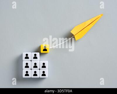 Yellow Paper Airplane zieht eine Führungskraft aus einer Gruppe von Mitarbeitern ab und repräsentiert das Konzept der Headhunting, Talentakquisition und Führung in Bu Stockfoto