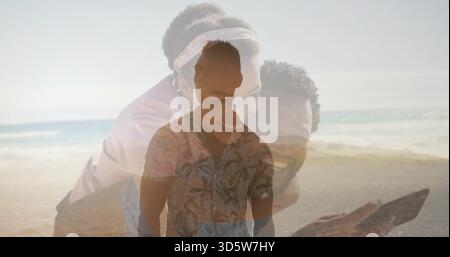 Lächelnder Mann mit gemustertem Blumenhemd, der am Strand steht, hinter dem Duo, das Telefon hält, Stirnband Stockfoto