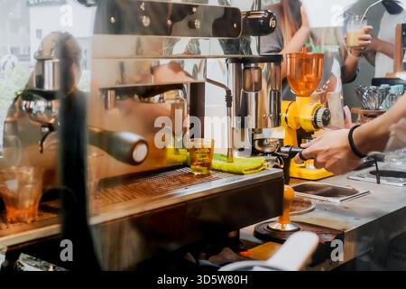Hände einer männlichen asiatischen Kaffeezubereiter für junge Erwachsene in Aktion, die Kundenbestellung in einem lokalen Café vorbereitet Stockfoto