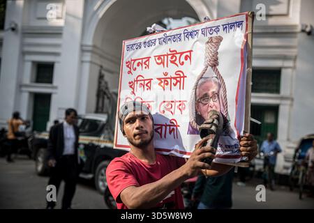 Dhaka, Bangladesch. November 2025. Ein Mann schlägt vor dem Internationalen Strafgerichtshof ein Poster des abgesetzten Premierministers von Bangladesch, Scheich Hasina, auf, nachdem sie wegen Verbrechen gegen die Menschlichkeit für schuldig befunden und zum Tode verurteilt wurde. Scheich Hasina floh im August 2024, nachdem viele Menschen bei der Niederschlagung der Proteste getötet wurden. (Foto: Sally Hayden/SOPA Images/SIPA USA) Credit: SIPA USA/Alamy Live News Stockfoto