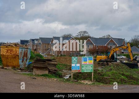Neue Häuser werden auf einem Brachfeld in Cowes auf der isle of wight gebaut, mit schweren Pflanzen und Sicherheitsschildern, die im Vordergrund sichtbar sind. Stockfoto
