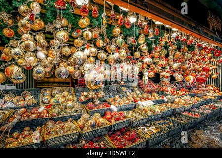 Goldene, rote und farbenfrohe Weihnachtsdekorationen hängen und füllen Korbkörbe und schaffen eine festliche Atmosphäre auf dem berühmten Wiener Weihnachtsmarkt. Stockfoto