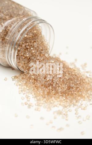 Klare Polymerpellets, die aus einem Kunststoffbehälter fließen Stockfoto