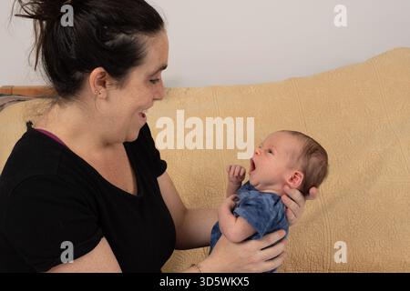 Neugeborener Junge, 3 Wochen alt, von Mutter gehalten Stockfoto