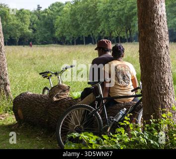 Paris, Frankreich - 14. Juni 2013: Unbekannte Männer und Frauen ruhen und rauchen im Wald von Vincennes nach dem Radfahren. Stockfoto