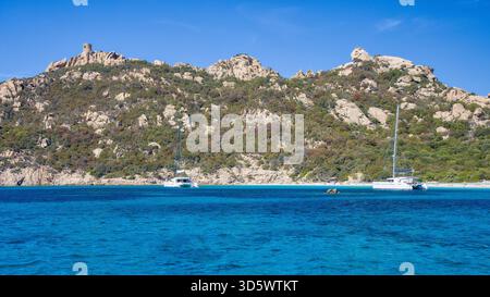Die Bucht von Roccapina mit ihrem wunderschönen türkisfarbenen Wasser vom Meer aus gesehen, mit dem Wachturm und liegendem Löwen auf dem Hügel in der Sonne Stockfoto