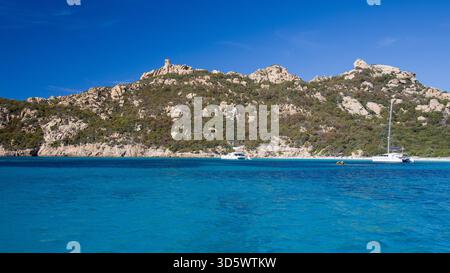 Die Bucht von Roccapina mit ihrem wunderschönen türkisfarbenen Wasser vom Meer aus gesehen, mit dem Wachturm und liegendem Löwen auf dem Hügel in der Sonne Stockfoto