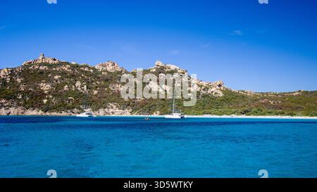 Die Bucht von Roccapina mit ihrem wunderschönen türkisfarbenen Wasser vom Meer aus gesehen, mit dem Wachturm und liegendem Löwen auf dem Hügel in der Sonne Stockfoto