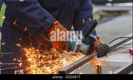 Ein Arbeiter schneidet einen Stahlträger mit einem Winkelschleifer. Stockfoto