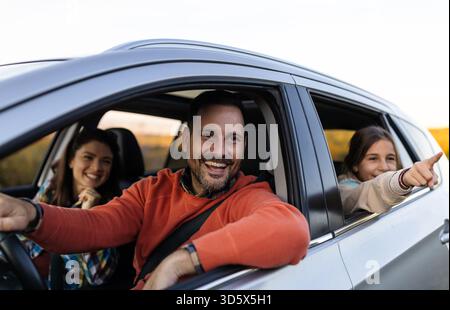 Eine Familie lächelt und lacht während eines Roadtrips in der Natur und genießt ihren glücklichen Moment zusammen Stockfoto