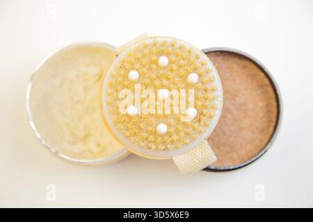 Runde Peeling-Bürste mit strukturierten Borsten, die neben natürlichen Hautpflegeprodukten platziert wird Stockfoto