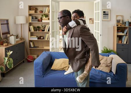 Reifer Schwarzer Mann, der einen Huckepack zu Black Boy in der Halle fährt Stockfoto